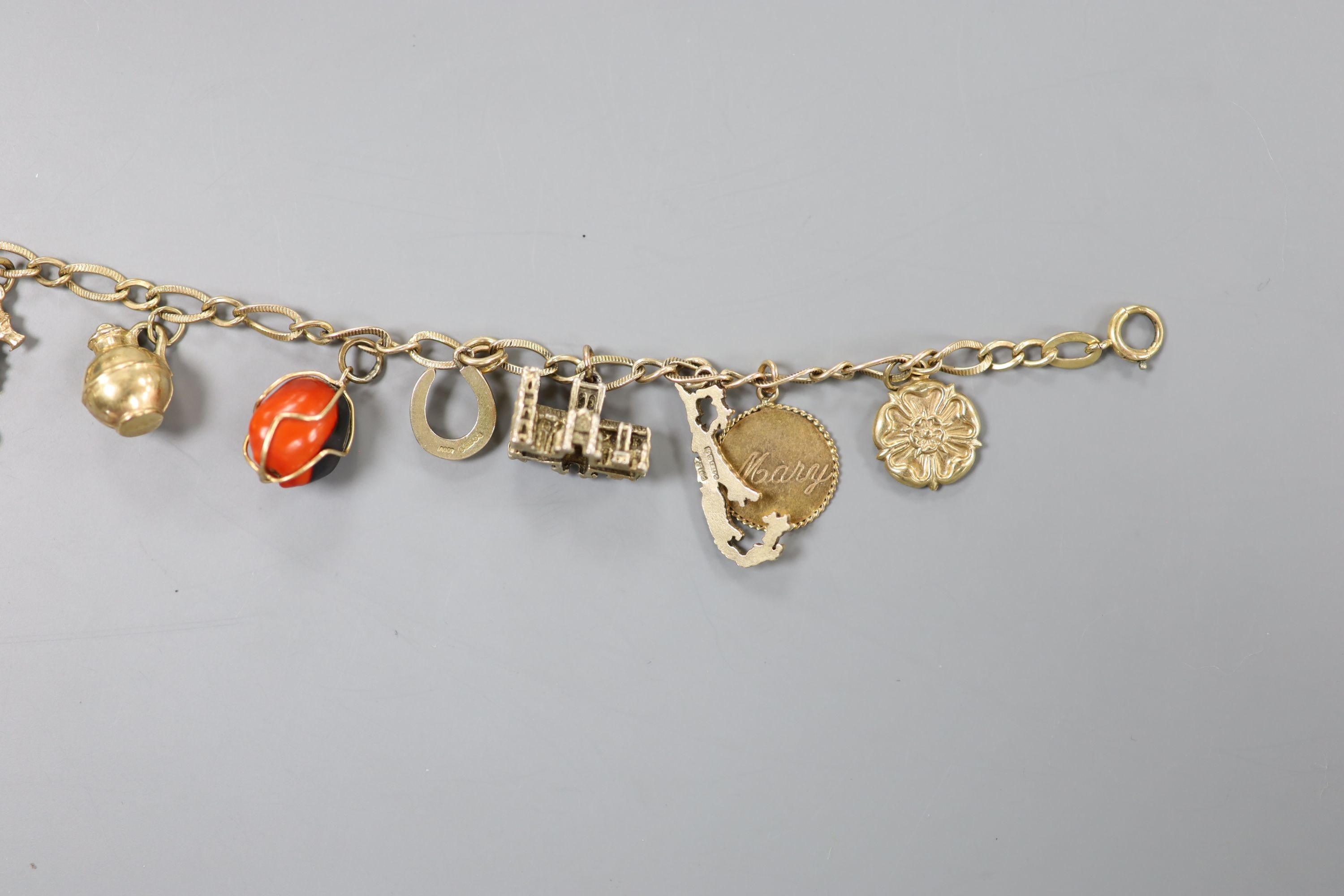 A 10k yellow metal oval link charm bracelet, hung with assorted mainly 9ct gold charms, gross weight 17.7 grams.